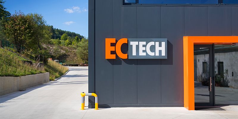 Modern dark grey building exterior with an orange 'ECTECH' sign and entrance.